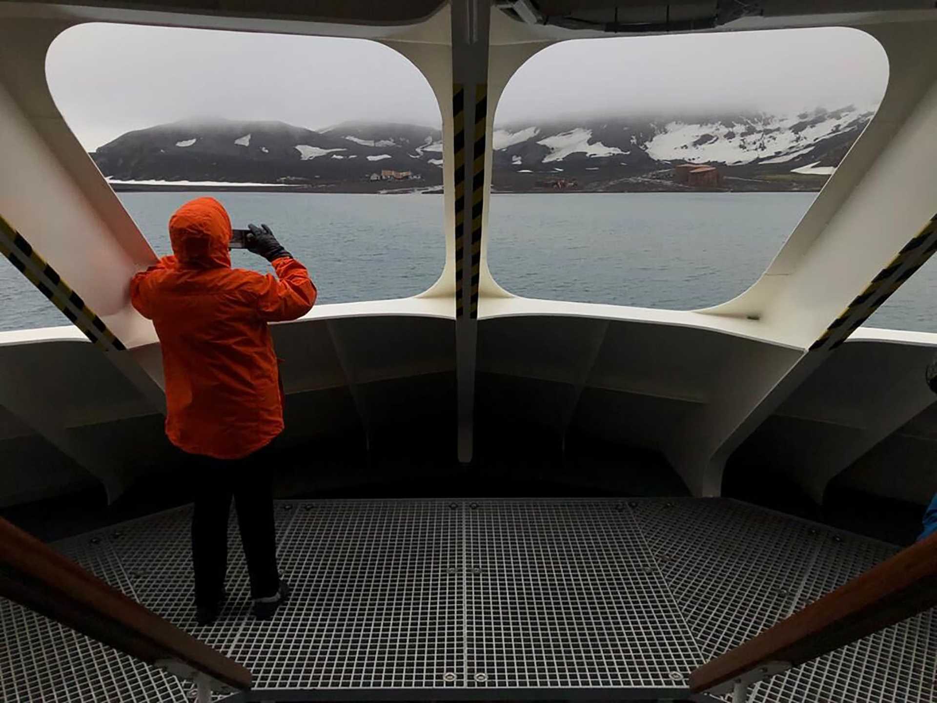 a person in an orange parka looks out the window of National Geographic Resolution