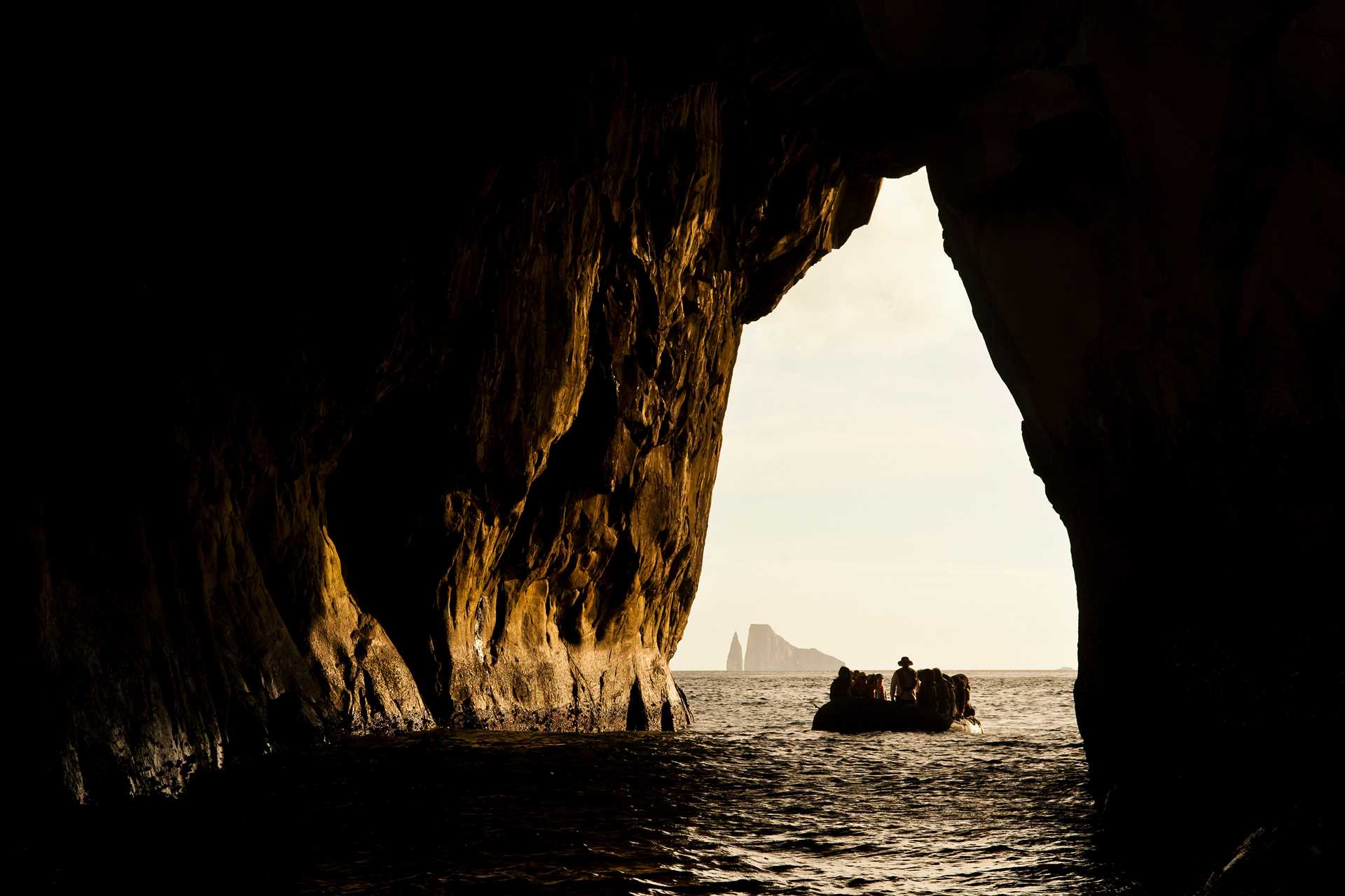 Guests sail into the rocky arch at Kicker Rock in a Zodiac in the Galápagos.