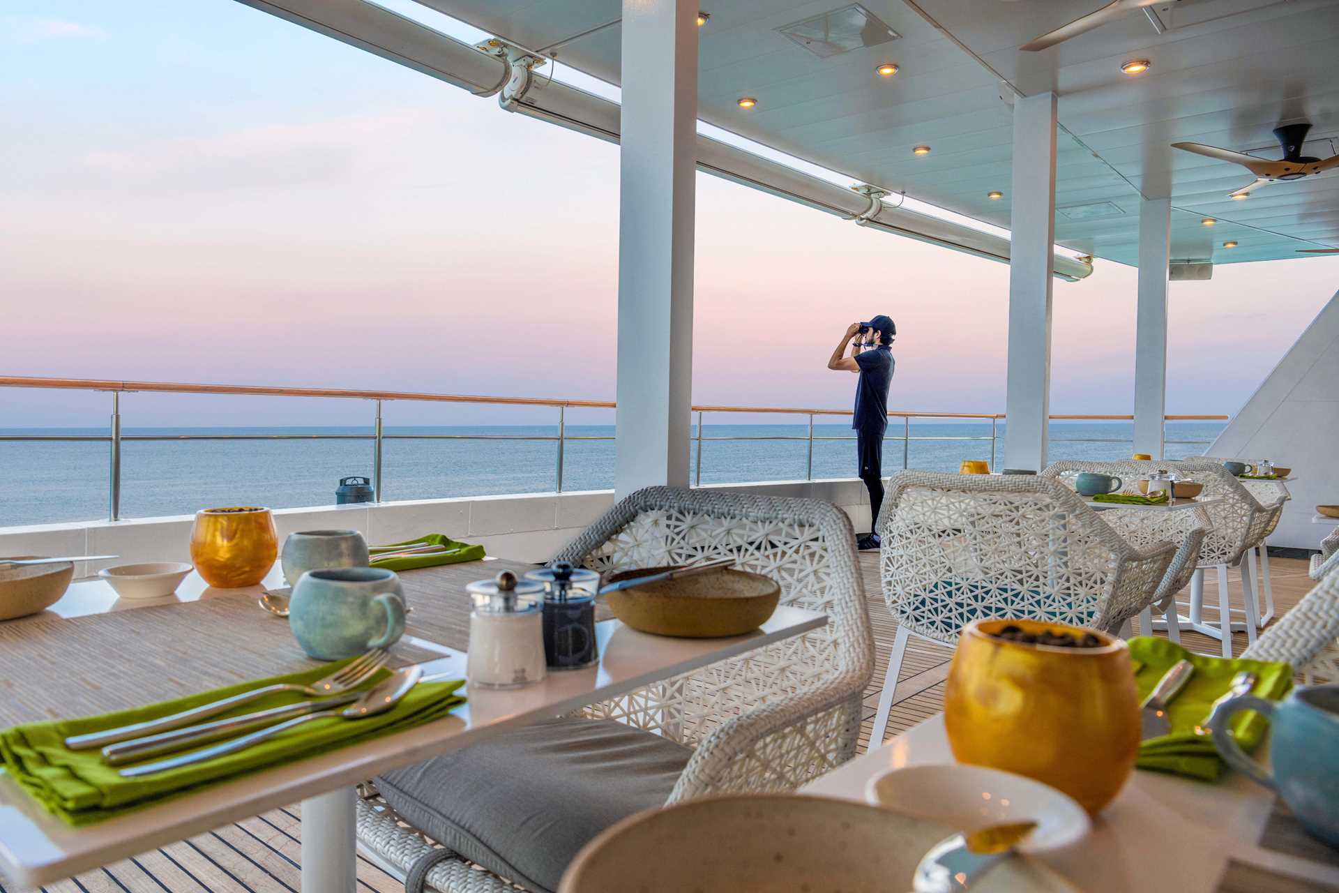 A guest looks out into the horizon from the deck of the ship National Geographic Islander II.