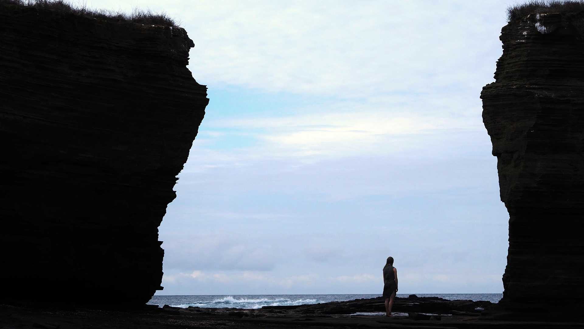 a human figure standing between two large cliffs